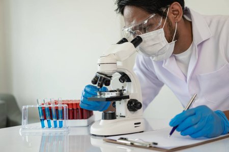 Photo for Scientist picks up sample tube of blue badger chemical along with analyzer in lab Technician holding test tubes in lab for research - Royalty Free Image