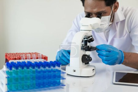 Foto de Científico recoge tubo de muestra de producto químico tejón azul junto con analizador en laboratorio Técnico que sostiene tubos de ensayo en laboratorio para la investigación - Imagen libre de derechos
