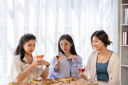 Téléchargez les photos : Groupe d'amies asiatiques à une fête Amusez-vous bien ensemble. pizza fête vin boissons Célébration d'un moment important - en image libre de droit