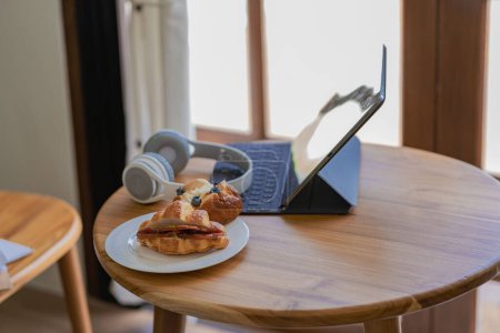 Foto de Cocina. Estuche de la tableta, auriculares en la mesa, concepto de trabajo matutino con comida. - Imagen libre de derechos
