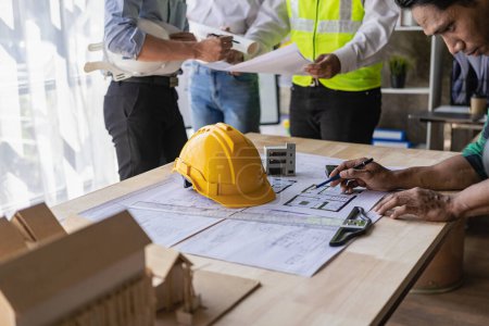 Photo for Engineer and businessman discussing construction project in office, team of engineers reviewing construction blueprints on new project with engineering tools at table in office - Royalty Free Image
