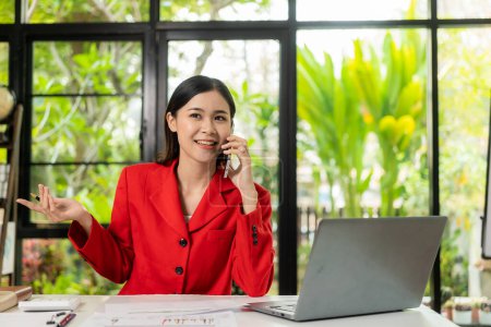 Téléchargez les photos : Femme comptable asiatique parlant au téléphone Elle est vendeuse dans une start-up. Appel aux clients pour vendre des produits et promotions Idées de vente de produits - en image libre de droit