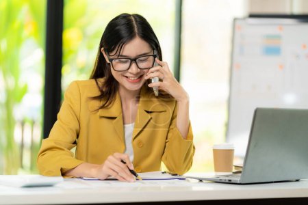 Photo for Asian female accountant talking on the phone She is a salesperson at a startup company. Calling customers to sell products and promotions Product selling ideas - Royalty Free Image