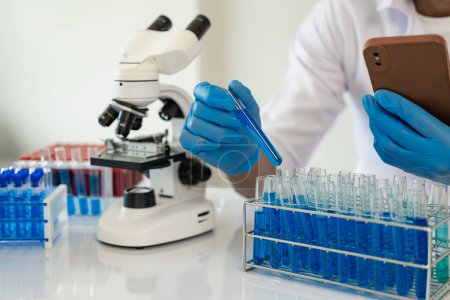 Photo for Doctor in mask examining DNA molecule in chemistry lab with scientist examining liquid sample with microscope in chemistry lab Researcher working with sample - Royalty Free Image