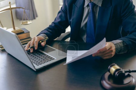 Photo for Male lawyer working at table in office focusing on scales of justice, lawyer holding pen and giving legal advice, business dispute service with hammer Close-up pictures - Royalty Free Image