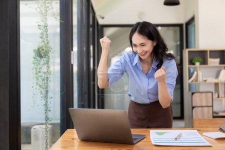 Photo for Happy, excited, success in business, Asian woman wins in office, beautiful Asian woman celebrates with laptop. happy success gesture ecommerce - Royalty Free Image