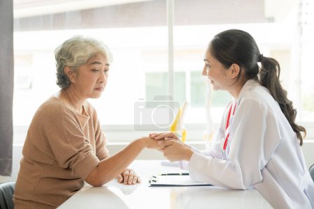 Photo for Elderly woman and female doctor in clinic office talk and discuss, Asian professional female doctor recommends health solutions to her elderly patient in examination room at hospital. - Royalty Free Image