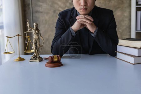 Photo for Asian male lawyer working in law office with hammer and scale and laptop, contract concept legal proceedings - Royalty Free Image