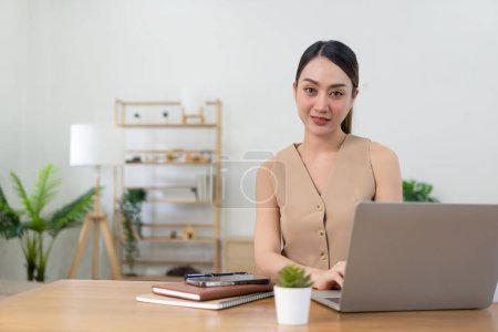Photo for Beautiful happy Asian freelance woman using laptop computer for remote work at home She communicates with service providers to provide online real estate consultations. - Royalty Free Image