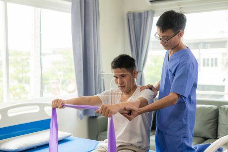 Foto de Médico fisioterapeuta que trata a un paciente cuyo brazo se está recuperando, haciendo fisioterapia para estirar los músculos en la clínica - Imagen libre de derechos