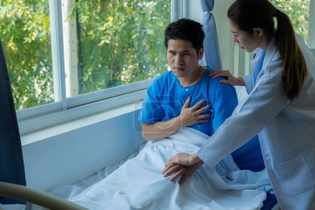 Foto de Un paciente masculino asiático yace en una cama de hospital y es cuidadosamente atendido por un médico. Médico dando consejos al paciente masculino Trabajando en el diagnóstico de enfermedades de salud - Imagen libre de derechos