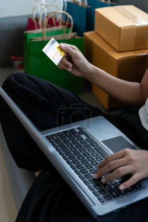 Téléchargez les photos : Online internet banking souriant main de jeune femme asiatique tenant une carte de crédit pour transférer ou payer sans espèces à la maison Technologie financière, concept de nom en ligne - en image libre de droit