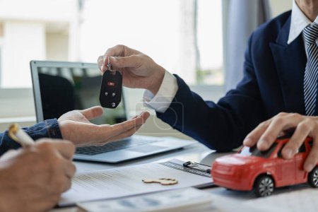 Photo for Car dealer hands keys to customer, closing car insurance documents or rental agreement or agreement. Buying or selling a new car, close-up photo - Royalty Free Image