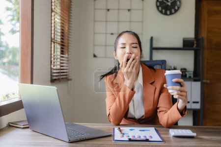Foto de Mujer de negocios estresada y cansada trabajando en computadora portátil con documentos financieros en el escritorio Concepto de síndrome de Office - Imagen libre de derechos