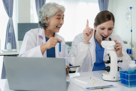 Téléchargez les photos : Deux belles jeunes scientifiques et femmes âgées travaillent dans un laboratoire avec des éprouvettes et font des recherches avec des éprouvettes faisant des recherches sur les produits chimiques bleus dans l'industrie de la santé. - en image libre de droit