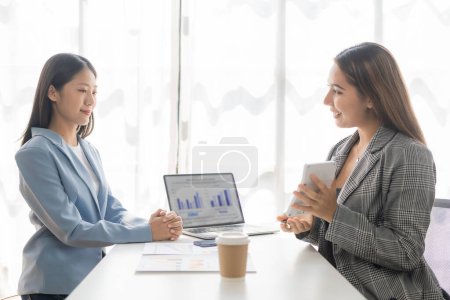 Photo for Asian businesswoman is discussing a new business project on a tablet. In a meeting, two people discuss investment projects on data charts and planning strategies. About new business - Royalty Free Image