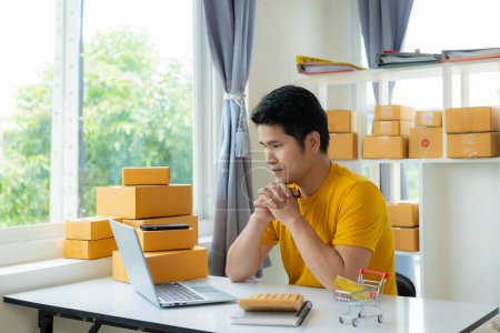 Photo for A young Asian male SME business owner sells products online and prepares product packaging boxes for sending online orders and having customers at home who are shopping online ready for delivery. - Royalty Free Image