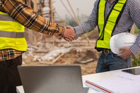 Photo for Architect and construction engineer holding hands while working for teamwork and cooperation concept after completing an agreement on construction site. Close-up pictures - Royalty Free Image