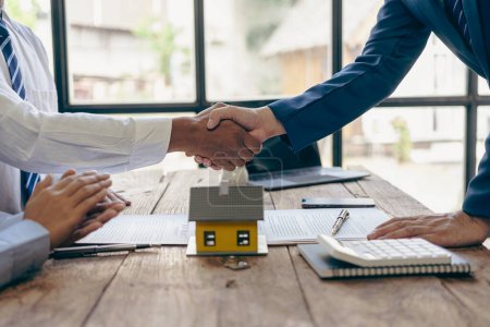 Photo for Real estate agent and customer shaking hands after signing a real estate business contract and home insurance with the customer to sign a contract to buy a house, congratulating the customer - Royalty Free Image