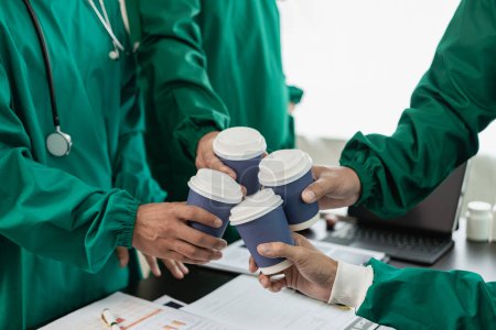 Téléchargez les photos : Équipe médicale tenant des tasses à café, cliquetis tasses à café, célébrer le succès, réunion de l'équipe pour réfléchir idées de traitement, photo en gros plan - en image libre de droit