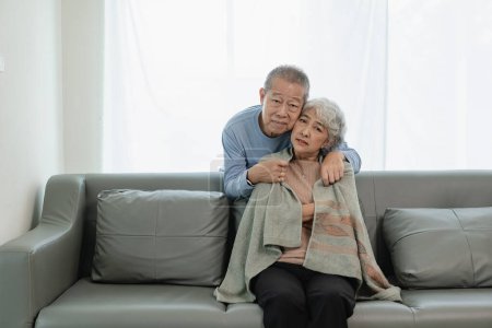 Photo for Asian senior couple looking at camera and smiling, senior smiling and looking at tablet Retired people use technology at home Woman hugging man with love Together forever on the sofa at home - Royalty Free Image