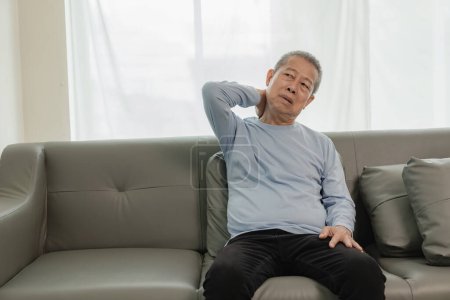 Foto de Asiático anciano hombre tiene dolor de espalda y enfermedad en la cama en casa, infeliz anciano tocando su espalda seriamente y tratando, concepto de cuidado de ancianos - Imagen libre de derechos