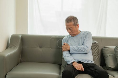 Foto de Un paciente asiático de edad avanzada sufre de dolor y entumecimiento en la mano de artritis reumatoide. Hombre mayor masajeando la mano con dolor en la muñeca concepto de problemas de salud - Imagen libre de derechos