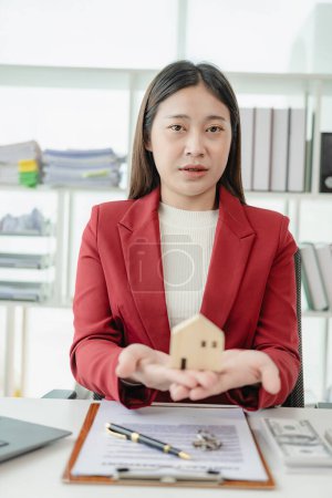 Téléchargez les photos : Asiatique femme agent immobilier employé recommande maison à client Expliquer l'intérieur de la maison et ultra-intérêts aux clients. Vente maison en ligne consultant - en image libre de droit