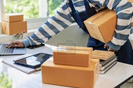 Der Verkäufer verpackt das Paket hinter der Versandbox. Vorbereitung von Paketen für das E-Commerce-Lieferservice-Konzept für KMU. Nahaufnahme.
