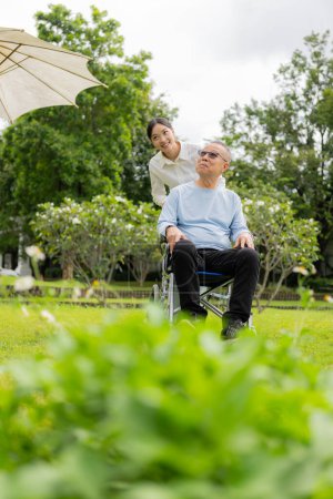 Téléchargez les photos : Infirmière asiatique soignant un vieil homme dans le jardin à la maison, infirmière soignante soutenant l'assurance maladie à la maison ou à l'hôpital, homme âgé - en image libre de droit