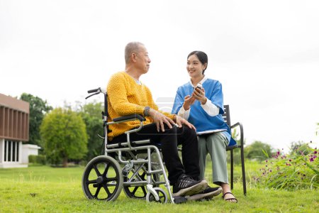 Téléchargez les photos : Infirmière asiatique soignant un vieil homme dans le jardin à la maison, infirmière soignante soutenant l'assurance maladie à la maison ou à l'hôpital, homme âgé - en image libre de droit
