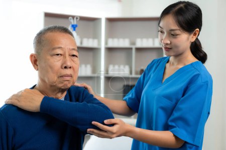 Téléchargez les photos : Un vieil homme asiatique fait de la physiothérapie avec le soutien d'une infirmière dans le salon en faisant de l'exercice pour un patient avec son soignant en soins infirmiers. Physiothérapie pour les personnes âgées - en image libre de droit