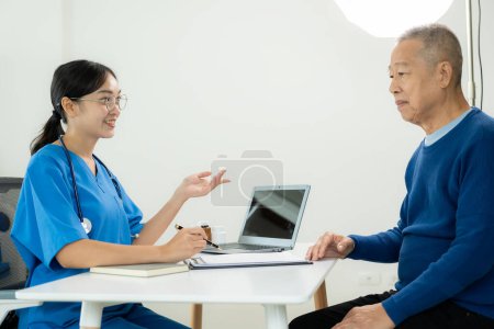 Foto de Asiático profesional médico femenino hablando con el paciente masculino acerca de su dolor y síntomas, mientras que dar consulta en la mesa en la sala de examen en el hospital de atención médica - Imagen libre de derechos