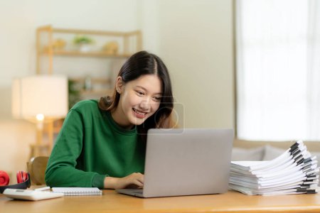 Téléchargez les photos : Ambitieuse fille asiatique travaillant à partir de la maison En regardant l'écran d'ordinateur portable et souriant, vérifier le courrier ou faire de la recherche tout en travaillant à distance, démarrage d'entreprise en ligne, télémarketing - en image libre de droit