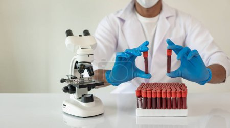 Photo for Hospital doctor holds blood vessel test in laboratory with blood sample from shelf with analyzer in lab - Royalty Free Image
