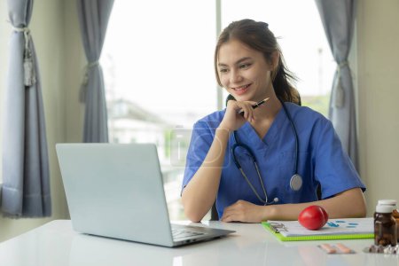 Photo for Beautiful young female doctor working with laptop Read electronic medical records Doctors provide online virtual consultations to patients. - Royalty Free Image