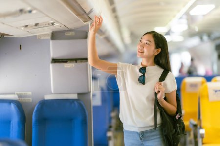 Téléchargez les photos : Airplane travel concept: Asian woman looking for a seat on the plane - en image libre de droit