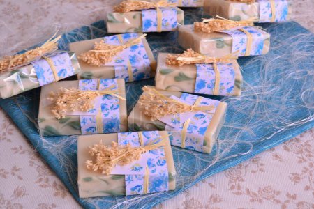 Téléchargez les photos : Cadeaux de savon artisanal rustique pour les invités, faveurs de fête nuptiale, savons vintage faits à la main décorés dans des couleurs naturelles, bleu fin vert - en image libre de droit