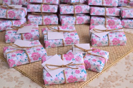 Spring summer wedding favors guest gift box with floral pink pattern and jute ribbon, beige wicker background, original party souvenirs handmade soap