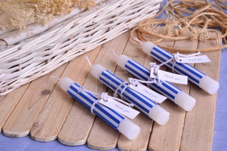 Summer wedding beach party favours white candles witn blue stripes pattern decoration, diy guest souvenirs, sailor nautical style, wood and wicker background, cotton ribbon and custom label