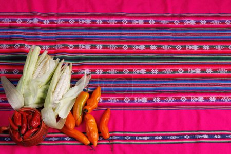 Photo for Aerial photo of products from the highlands of Peru. Choclo, aji amarillo, aji rojo on a tablecloth with the typical design pattern of the Inca Andina sierra of Peru, Bolivia, Ecuador - Royalty Free Image