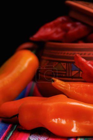 Photo for Bowl full of red chili peppers decorated with fretwork and colors full of hot chili peppers and yellow chili peppers on top of a typical tablecloth from the highlands of Peru. On a typical tablecloth - Royalty Free Image