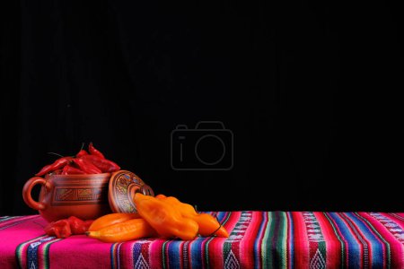 Photo for Bowl full of red chili peppers decorated with fretwork and colors full of hot chili peppers and yellow chili peppers on top of a typical tablecloth from the highlands of Peru. On a typical tablecloth - Royalty Free Image