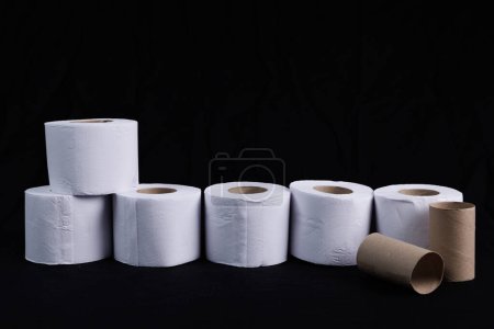 Photo for Toilet paper to go to the bathroom in a column with worn paper rolls and on a black background - Royalty Free Image