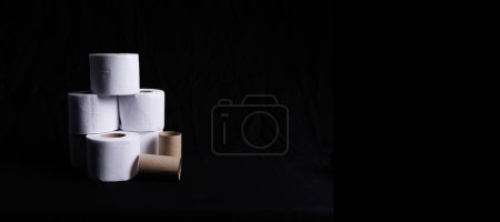 Photo for Toilet paper to go to the bathroom in a column with worn paper rolls and on a black background - Royalty Free Image