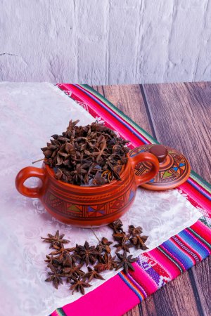 Photo for Clay jar containing star anise on an old wooden table and with a tablecloth from the highlands of Peru - Royalty Free Image