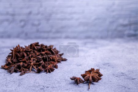 Photo for Mountain of highly scented star anise with a few stars of anise in focus on a cement table and with the wall painted white - Royalty Free Image