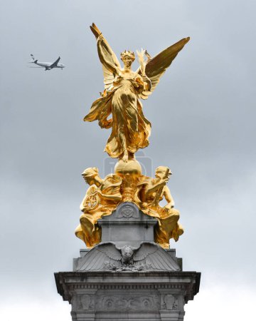 Photo for Gold statue on top of The Victoria Memorial, depicting a Gilded Winged Victory standing on a globe and with a victor's palm. The Mall, London - Royalty Free Image