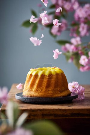 Téléchargez les photos : Gâteau de lapin glacé jaune. Chute des pétales de fleurs de cerisier. Le printemps est prêt. gâteau lapin thème de Pâques. - en image libre de droit