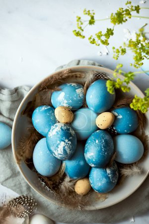Téléchargez les photos : Image lumineuse d'œufs de Pâques bleus dans un bol en céramique. Fond en marbre clair. Festive Pâques photographie nature morte. Image verticale avec un peu d'espace pour la copie. - en image libre de droit